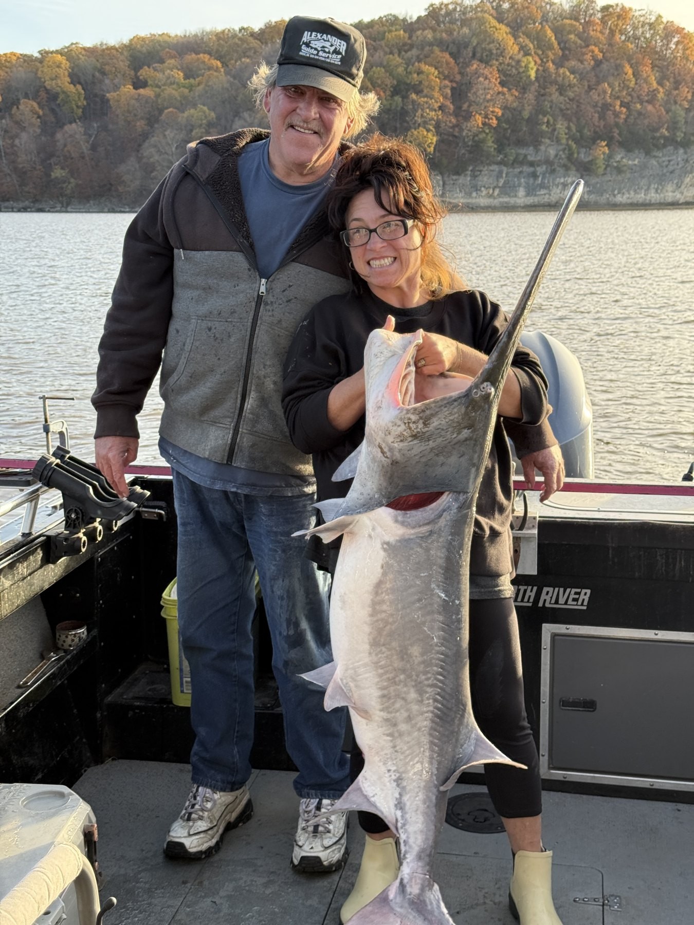 Two smiling anglers with a large paddlefish on Grand Lake